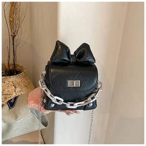 Detail of a mini black bow handbag with silver turn-lock and chain strap