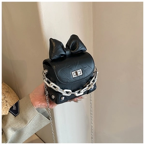 Detail of black mini box bag featuring a top bow decor and silver metal chain strap
