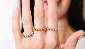 Three minimalist spinner rings in gold, silver, and rose gold on a model's hand