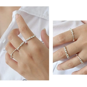 Detail shot of silver rotating beads on stress relief ring against white fabric background