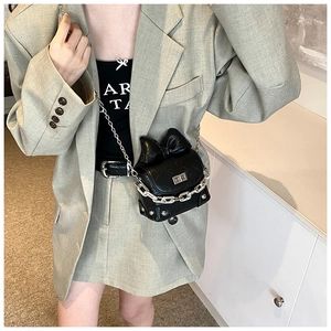 Detail of a black mini bow crossbody bag with silver chain and metal turn-lock closure