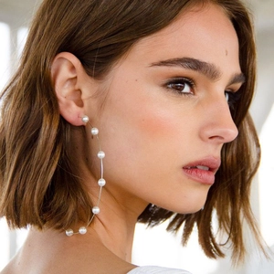 Nahaufnahme eines Models mit großen Creolen mit weißen Perlen im klassischen Stil
