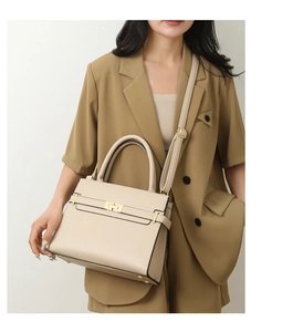 Détail d'un sac à main trapèze beige avec boucle en métal et texture litchi sur modèle