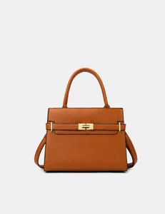 Détail d'un sac à main marron caramel avec texture grainée et fermoir pivotant doré