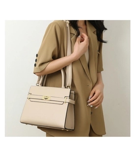 Sac à main structuré beige crème avec fermoir doré porté sur une veste de costume