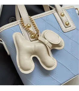 Détail du sac seau matelassé bleu clair avec un charmant chiot beige et des clous dorés
