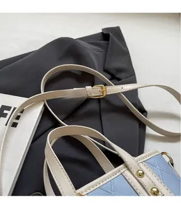 Détail de la bandoulière réglable crème avec boucle dorée sur un sac seau matelassé