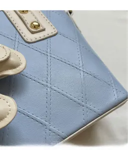 Détail du sac seau matelassé bleu clair avec rivets dorés et bordure ivoire