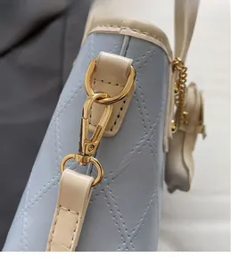 Détail du sac seau matelassé bleu clair avec crochet doré et bordure contrastée