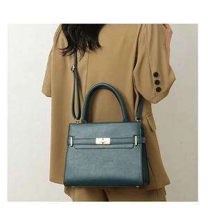 Détail d'un sac à main en cuir vert foncé à grain lychee avec fermoir doré et bandoulière