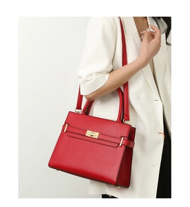 Détail d'un sac à main rouge en cuir grainé avec fermoir rotatif doré sur modèle