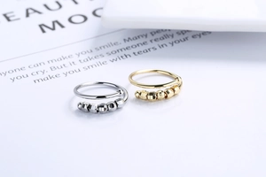 Close-up of gold and silver spiral fidget rings with rotating metal beads on a card