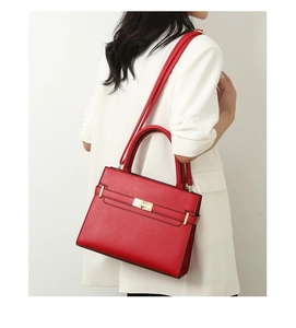 Détail du sac à main rouge en cuir texturé avec boucle dorée porté par un mannequin