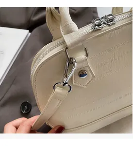Detail of off-white crocodile embossed leather bag with premium silver hardware zipper