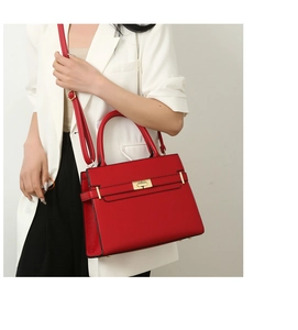 Détail d'un sac à main rouge en cuir grainé avec fermoir doré et bandoulière réglable