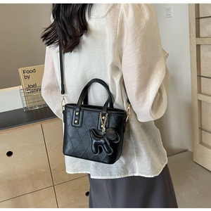 Détail du sac seau noir matelassé avec un charm de chiot et une bandoulière réglable