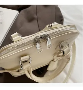 Detail of smooth metal double zippers on off-white leatherette shell handbag