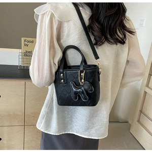 Détail du sac seau noir matelassé avec chaîne dorée et breloque en forme de chien