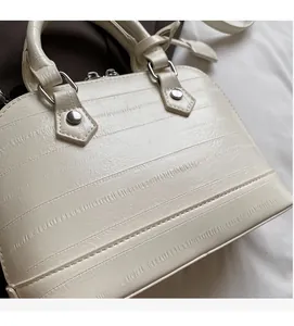 Detail shot of white shell bag featuring textured faux leather and silver metal studs