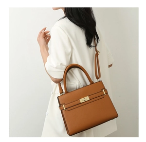 Gros plan d'un sac à main en cuir marron avec boucle dorée sur un blazer blanc élégant
