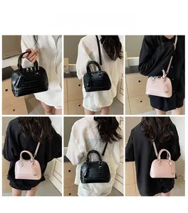 Detail showing shell-shaped crossbody bags in black and pink with crocodile texture