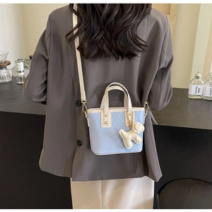Détail du mini sac seau matelassé bleu clair avec charm chien et anses crème