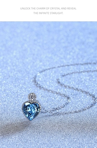 Detail of heart crystal necklace in sea blue with silver chain on sparkling background