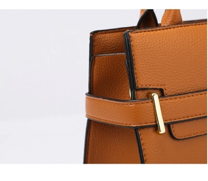 Détail de cuir grainé marron-orange avec ferrures dorées et boucles décoratives de sac