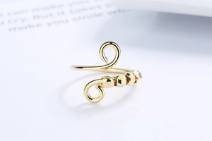 Detail of gold spiral anti-anxiety ring with geometric faceted beads on a white surface