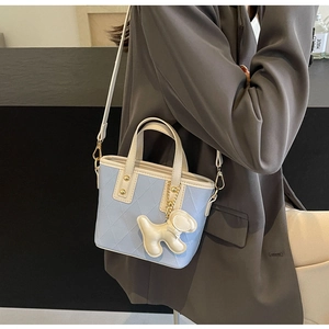 Détail du sac seau matelassé bleu clair avec breloque chien et bandoulière blanc crème