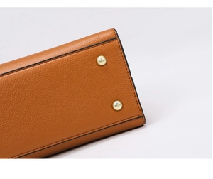 Détail du fond de sac en cuir marron avec clous de protection en métal doré brillant