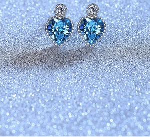 Detail of silver heart earrings with faceted blue gemstones and small clear crystals