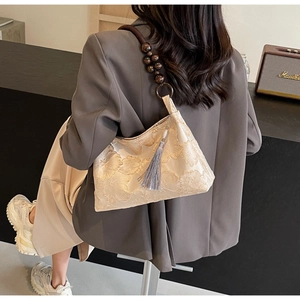 Detailed texture of jacquard fabric bag with wooden bead strap and silk tassel accent