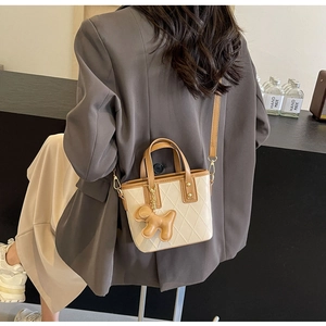 Détail du sac bandoulière matelassé beige avec lanières en cuir marron et breloque chien