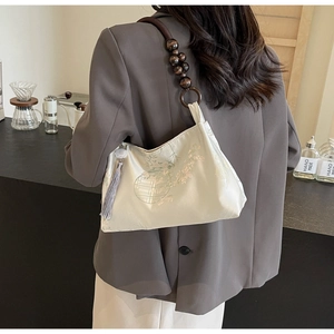 Detail of beaded wood strap and grey tassel on a floral jacquard Chinese style bag