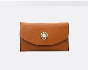 Détail de la pochette enveloppe en cuir litchi marron avec boucle dorée et perle élégante