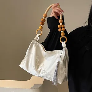 Detail of floral embroidery on ivory silk bag with wooden bead handle and tassel