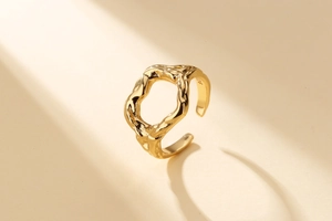 Détail d'une bague dorée ajustable avec texture irrégulière et gravure S925 à l'intérieur