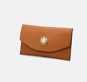 Détail d'une pochette enveloppe en cuir caramel avec boucle cœur en perle métallique