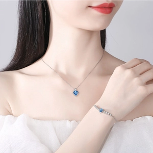 Silver-plated heart jewelry set with blue heart crystals on model neck and wrist