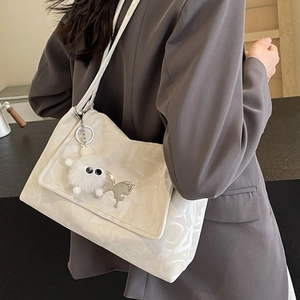 Elegant white tote bag with silver butterfly charm and plush detail on grey blazer