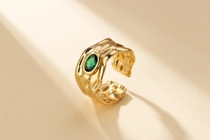 Macro shot of irregular lava texture gold ring with oval green zircon and open band