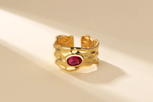 Detailed view of adjustable gold ring featuring hammered texture and a red oval zircon