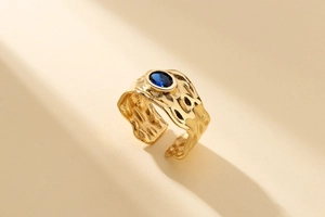 Macro shot of gold-plated 925 silver ring with irregular texture and blue gemstone
