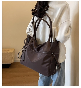 Detail of dark brown large canvas tote bag with leather straps and zipper detail