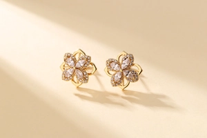 Detail view of gold-plated clover earrings with micro-set cubic zirconia and floral design