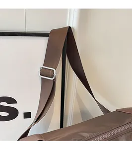 Detail of adjustable wide shoulder strap and metal buckle on brown canvas tote bag