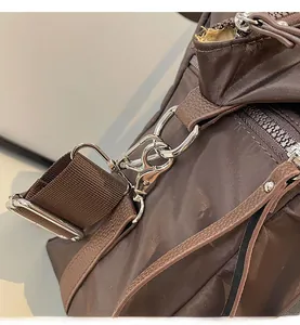 Macro view of glossy silver metal hooks and reinforced brown leather trim on canvas bag