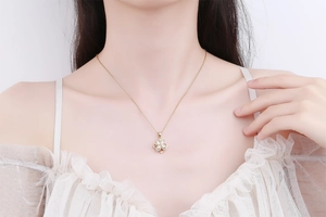 Close-up of golden four-leaf clover pendant necklace with micro-set zircons on model