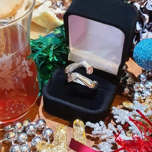 Detail of silver hug ring with realistic hands design in a black velvet gift box